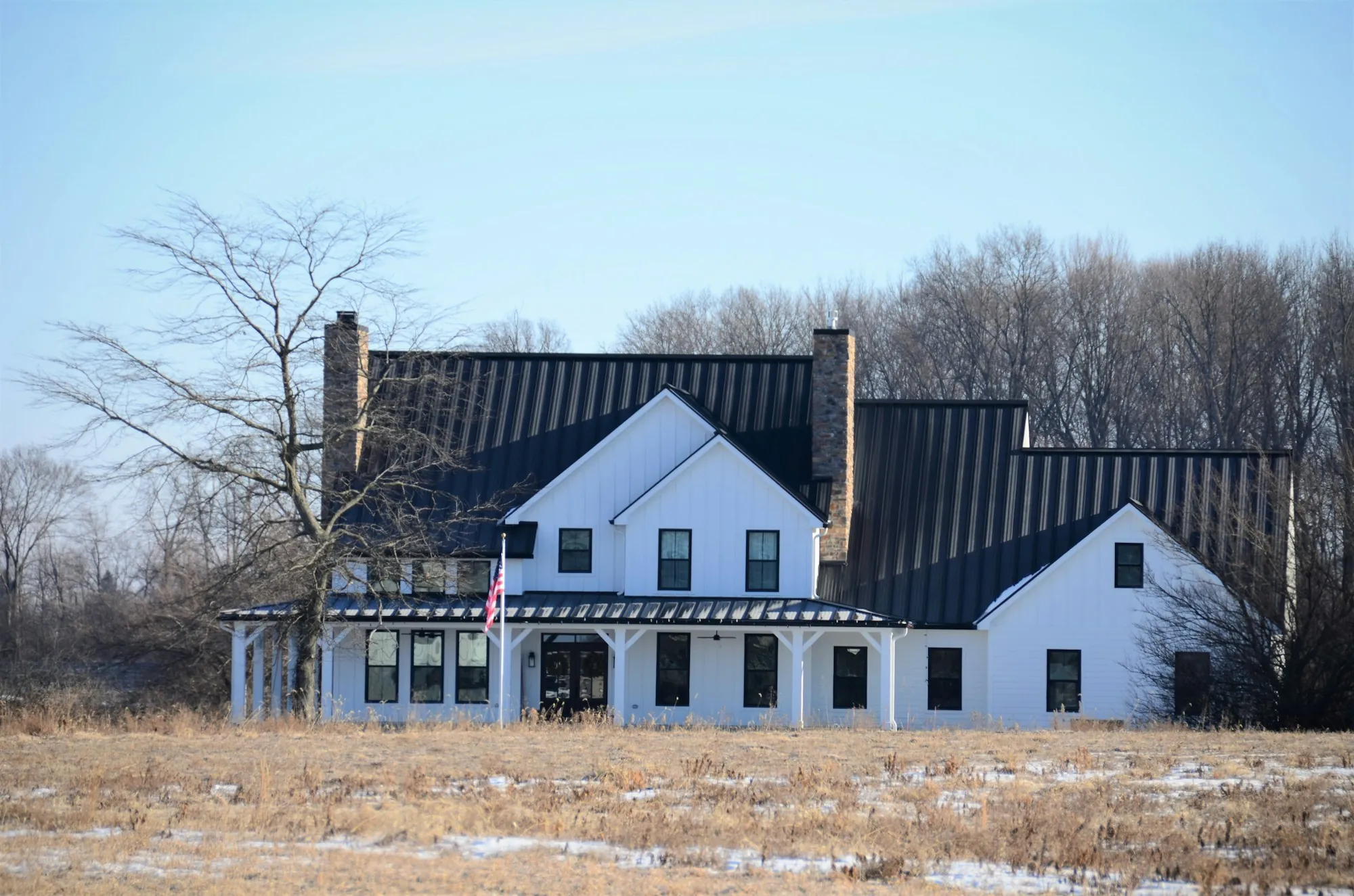 White farmhouse with a black standing seam metal roof