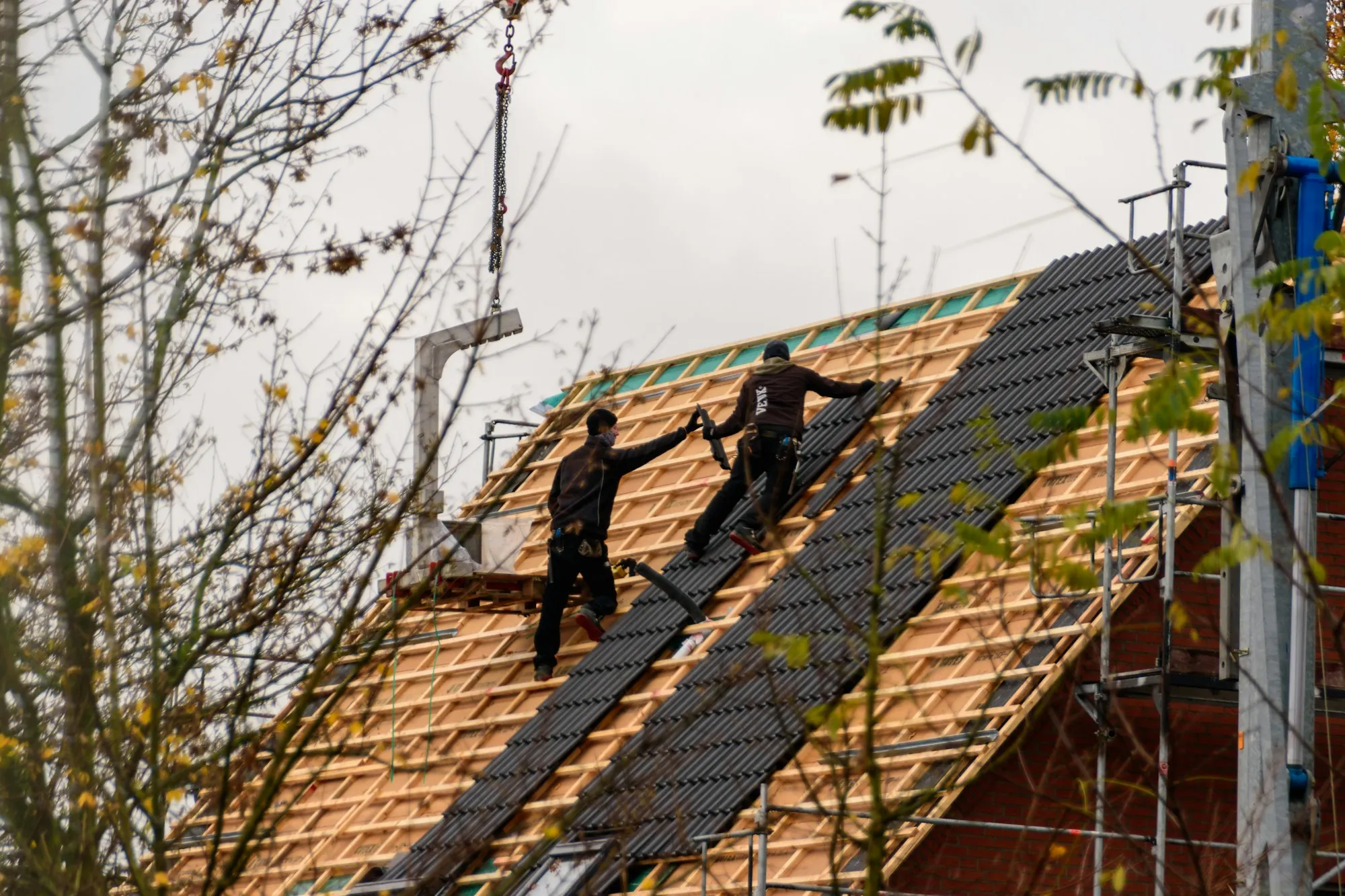 Two roofers working on bare roof battens during a re-roof