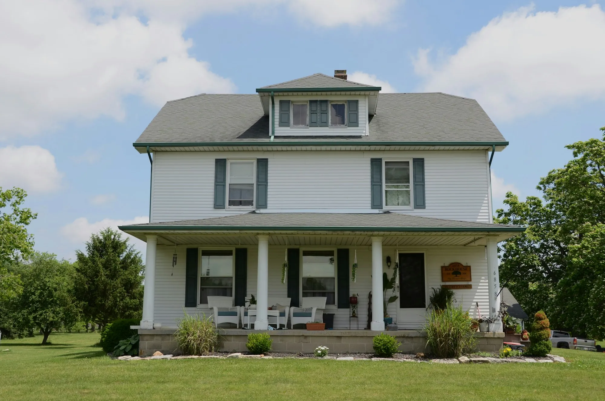 White farmhouse with a gray shingle roof and dormer