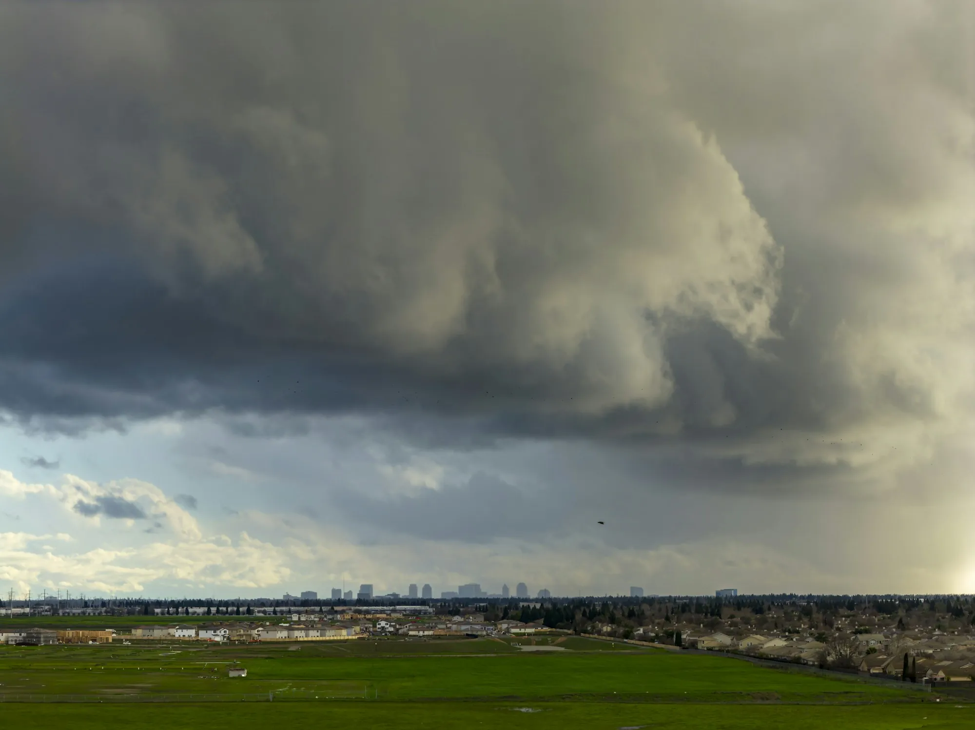 Towering storm clouds over a city on the horizon