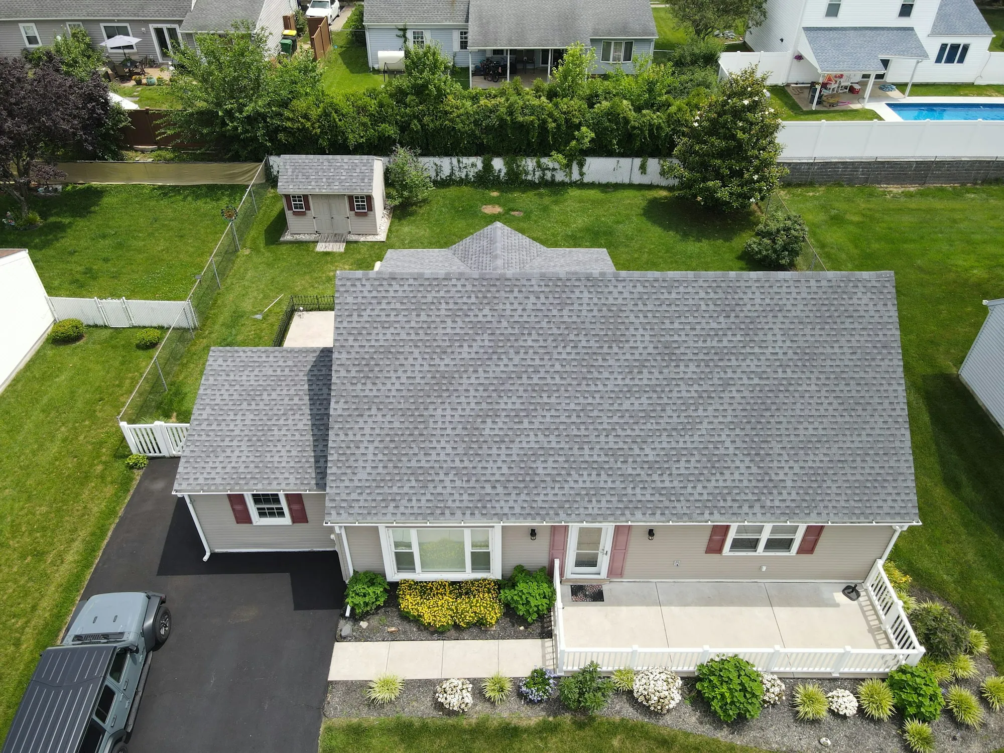 Aerial view of a gray shingle roof on a small house with a green lawn, the kind of roof weighed for leak repair or replacement in Suwanee